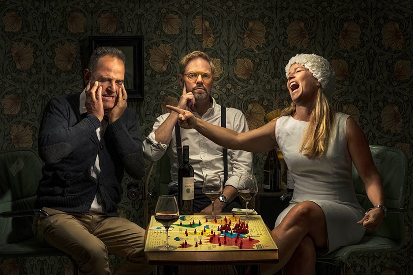 Three people playing games and drinking wine